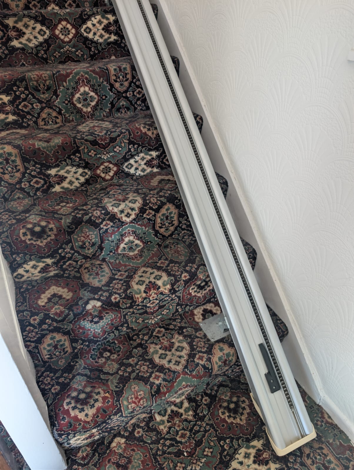 Stairlift rail on staircase showing rack and gear track during cleaning